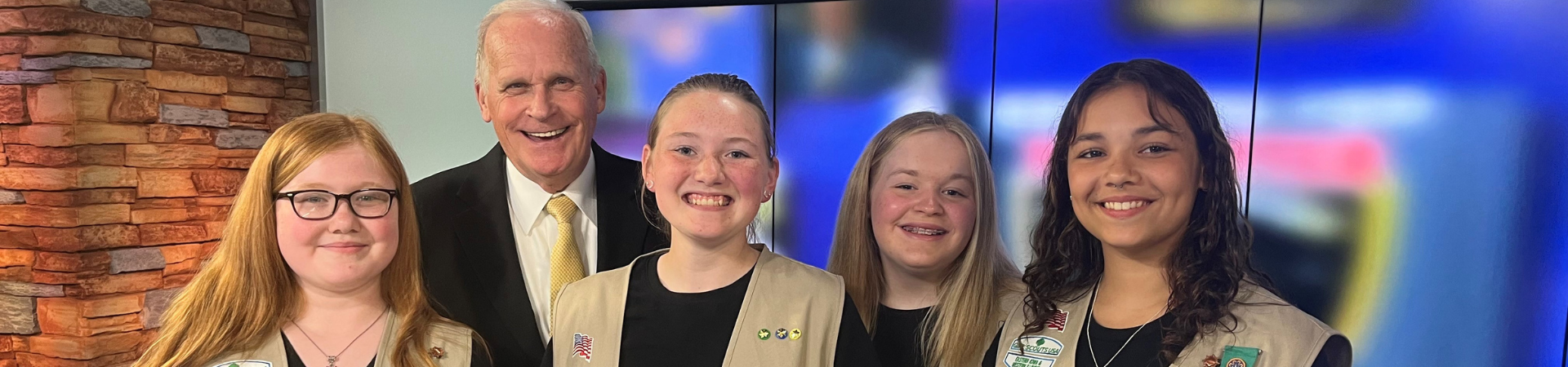  Older Girl Scouts and a local news anchor 