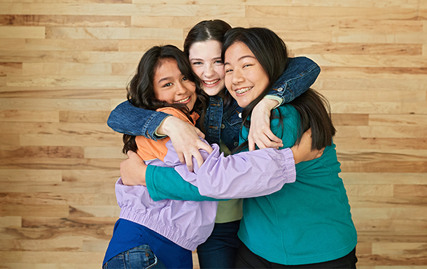 Three girls smiling and hugging