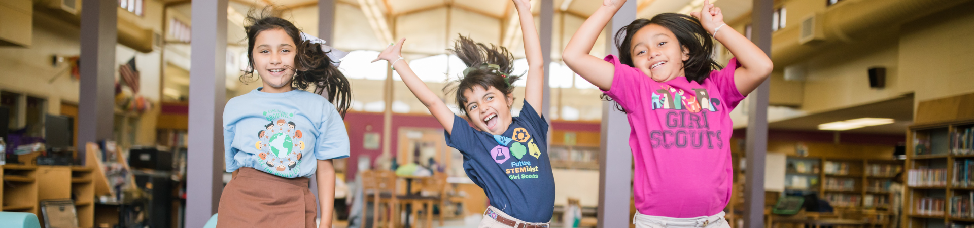  Three girls smiling and jumping in Girl Scout t-shirts 