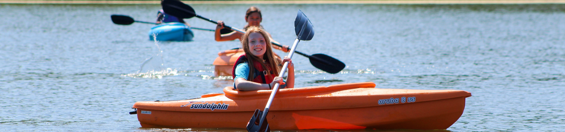  two girls kayaking across a lake 