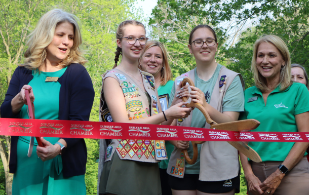 girl scouts and board member cutting a ribbon at a camp property